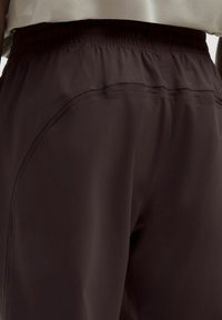 Dunkelbraune Sportshorts mit einem elastischen Bund. Mit seitlichen Paneeldetails und einer glatten, leichten Textur.
