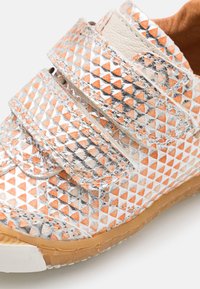Buty na rzepy z teksturową powierzchnią, z wzorami w srebrne i pomarańczowe trójkąty. Gumowa podeszwa, jasnobeżowe akcenty i solidna konstrukcja.
