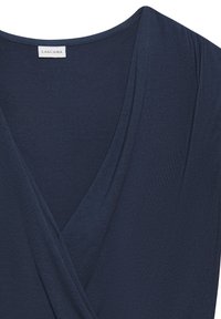 Haut sans manches bleu foncé à col en V avec un design croisé devant et une petite étiquette de marque à l'intérieur de l'encolure.
