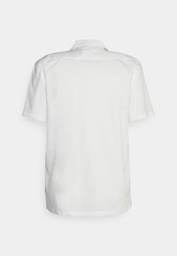 Bílá košile s krátkým rukávem vyrobená z měkké látky s hladkým povrchem. Má klasický límec a rovný lem se bočními rozparky.