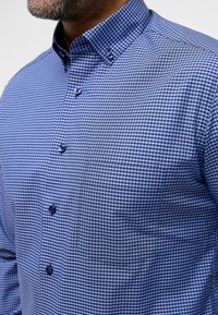 Camicia a quadri blu e bianchi con colletto button-down, bottoni frontali e taschino sul petto, realizzata in tessuto liscio.