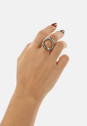 Zilverkleurige metalen ring met een geometrisch, open driehoekig ontwerp. Gladde textuur en gepolijste afwerking aan de hand van een model.