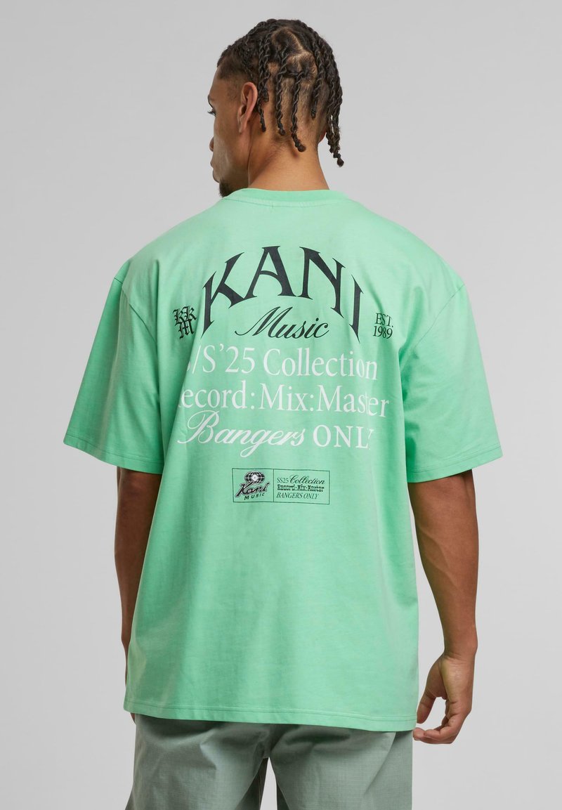 Mint green oversized t-shirt featuring bold black text and graphics on the back, with a relaxed fit and short sleeves.