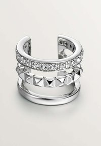 Anillo multi-banda de plata que presenta una fila de cristales claros, tachuelas en forma de pirámide y bandas circulares lisas, exhibiendo diversas texturas y un alto brillo.