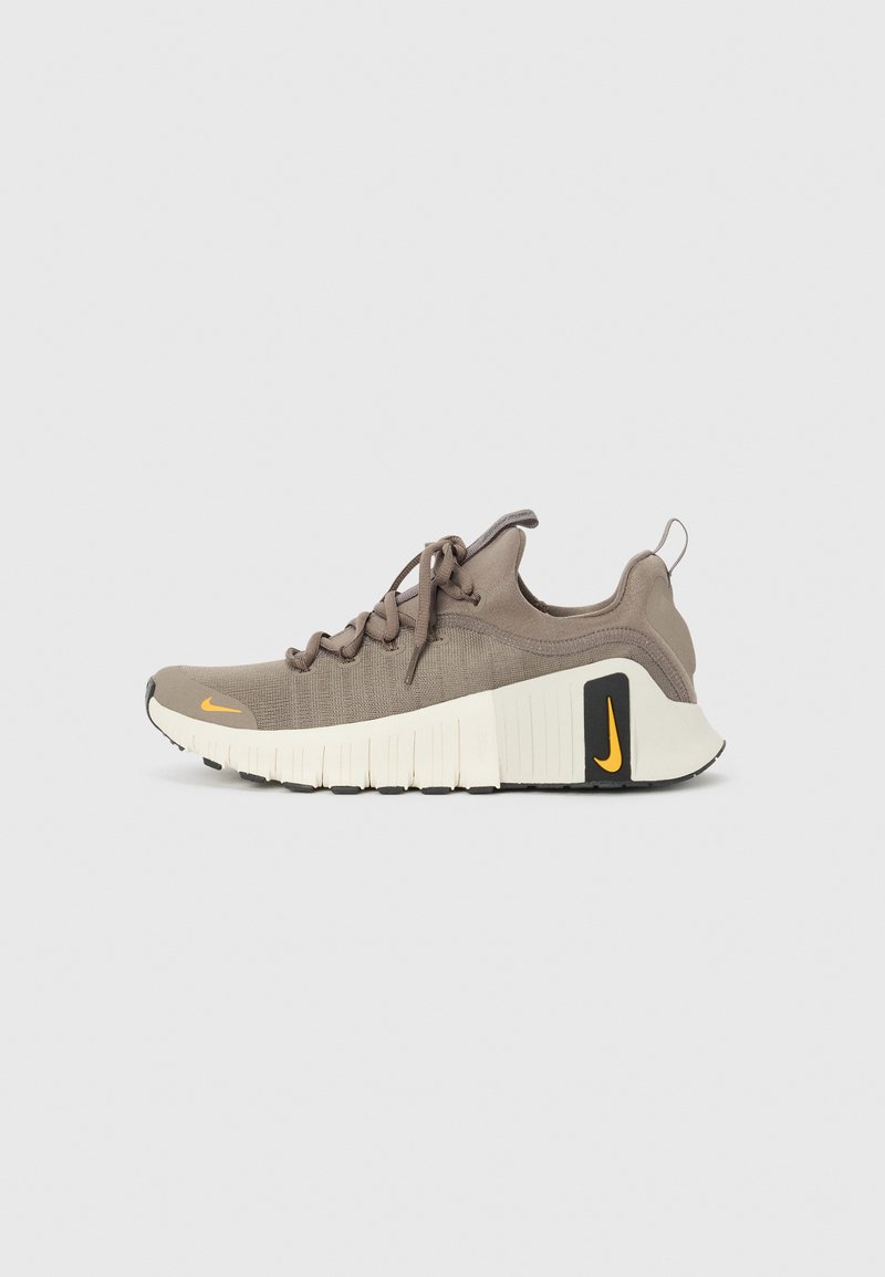 Brune netmesh sneakers med en tekstureret overdel, forstærket tå, tyk hvid sål, sorte detaljer og et lille orange logo på siden.