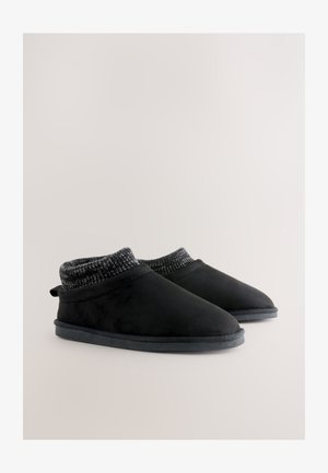 Melnas čības ar maigu zamšāda faktūru, pelēku adītu aproci un noapaļotu purngala dizainu. Tās ir aprīkotas ar izturīgu, teksturētu melnu zolīti.