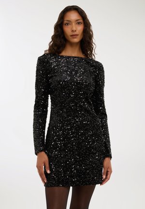 Vestito nero con paillettes, maniche lunghe, scollatura a barca e silhouette aderente. Texture lucida con paillettes densamente distribuite in tutto il capo.