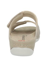 Beige sandal with Velcro strap, textured material, soft insole, and white rubber sole. Minimalist design with no embellishments.