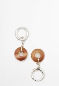 Orecchini in resina con componenti circolari di colore marrone e accessori in tonalità argento. Presentano una texture liscia con un centro cavo in ogni disco.