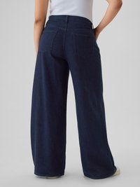 Pantaloni din denim întunecat, cu croială largă, talie înaltă, două buzunare posterioare și tiv curat. Materialul are o textură netedă și rezistentă.