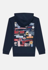 Sudadera de marina con un estampado gráfico que presenta títulos y logotipos de cómics, incluyendo "Batman" y "Superman", en varios colores y estilos.