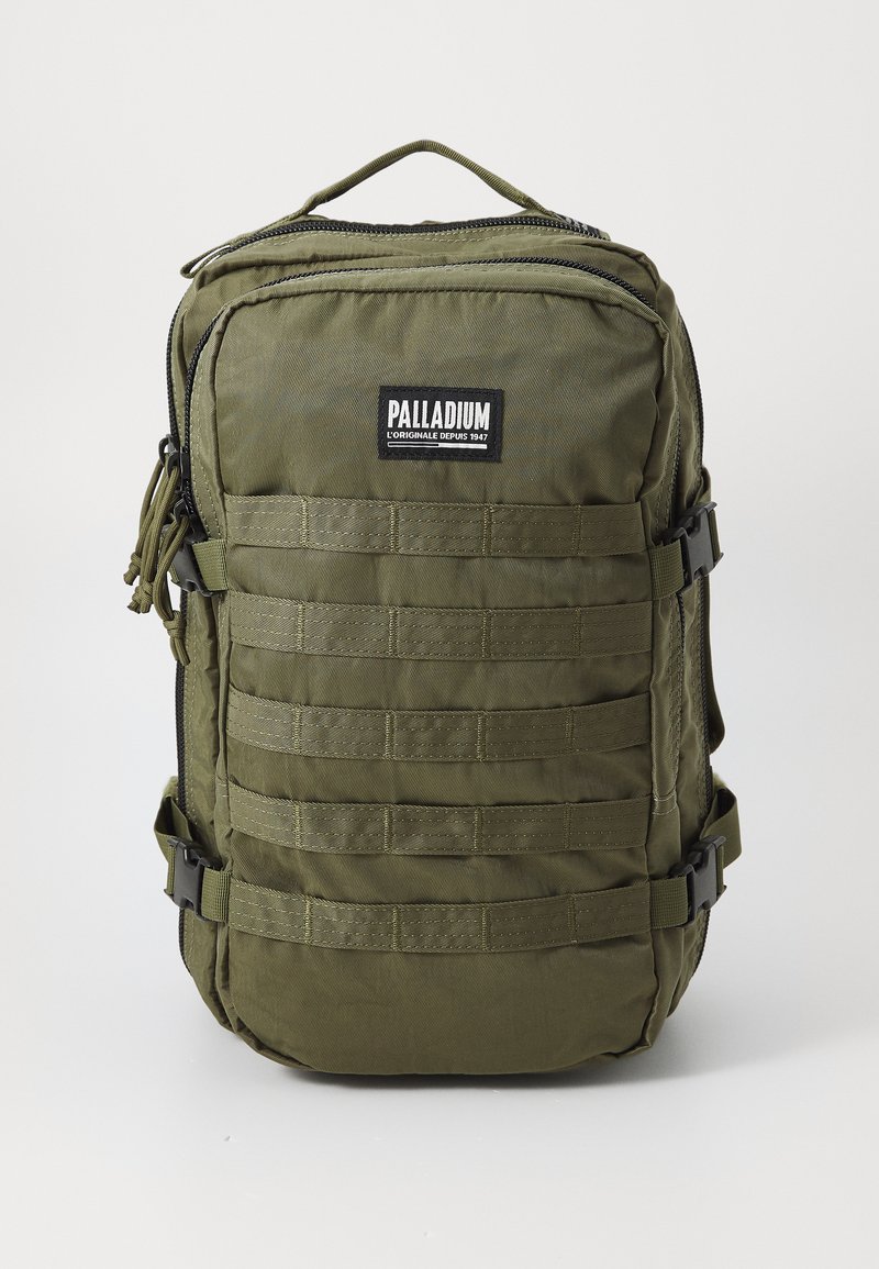 Zaino in nylon verde oliva con zip, fasce in rete frontali, logo PALLADIUM e maniglia superiore per il trasporto. Dotato di cinturini laterali regolabili.