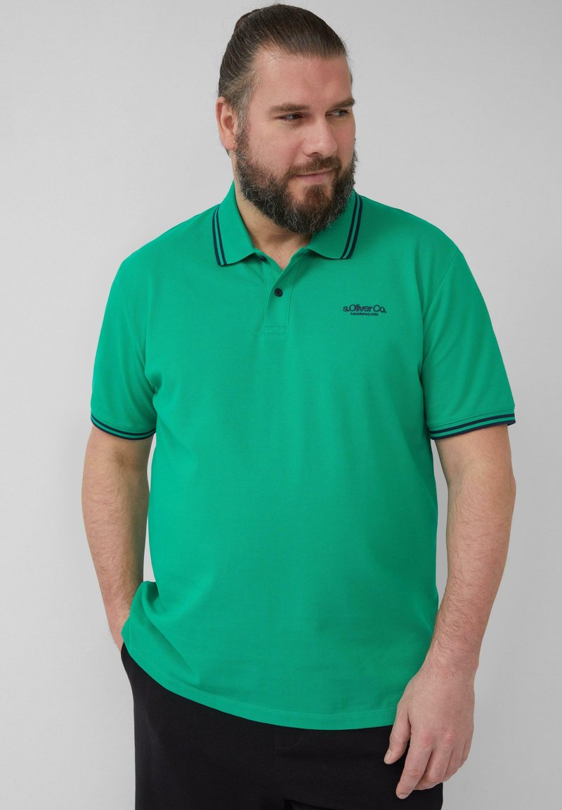 Groene polo met contrasterende marineblauwe kraag en mouwafwerking. Voorzien van een klein logo op de borst. Gemaakt van een gladde stof.