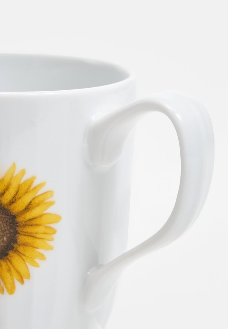 Biała ceramiczna filiżanka z jasnym żółtym wzorem słonecznika. Posiada gładką powierzchnię i zaokrągloną rączkę, idealną do wygodnego chwytu.