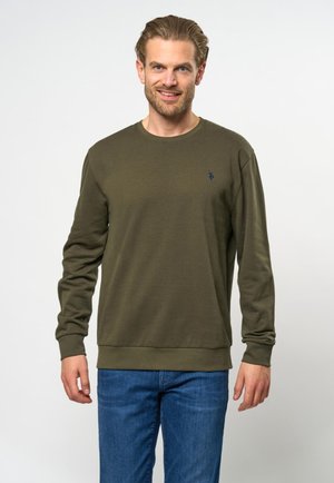 Olivgrüner Sweatshirt mit Rundhalsausschnitt, langen Ärmeln und gerippten Bündchen. Verfügt über ein kleines blaues Emblem auf der Brust. Kombiniert mit blauen Jeans.
