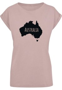 Rosa bomulls t-skjorte med korte ermer som har en svart silhuett av Australia og teksten "AUSTRALIA" i hvitt. Enkel design, avslappet passform.