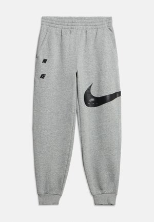 Gaiši pelēkas sporta bikses ar elastīgu jostu un aprocēm, sānu kabatām, melnu Nike logotipu uz kreisā augšstilba un lielu Swoosh zīmogu uz labā augšstilba.