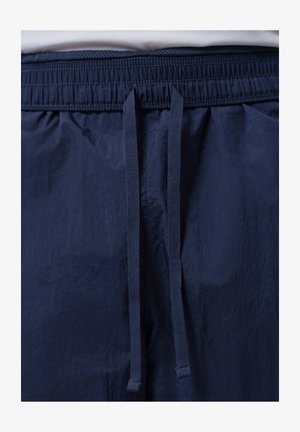 Shorts à taille élastique bleu marine avec un cordon de serrage central à l'avant noué en un nœud lâche.