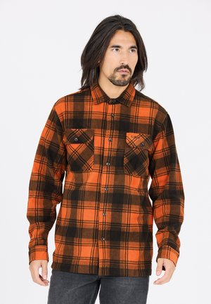 Orange og sort ternet flannel skjorte med knaplukning, to brystlommer og lange ærmer, lavet af et uld-lignende tekstureret stof.
