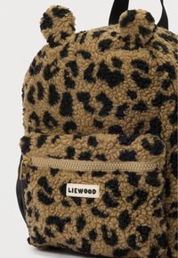 Mały brązowo-czarny plecak w cętki z futrzanym wykończeniem z zaokrąglonymi uszami, przednią kieszenią na zamek błyskawiczny oraz metką "LIEWOOD" na kieszeni.