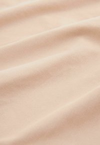 Tessuto beige, morbido e con una texture liscia; le pieghe creano onde delicate, mostrando un colore uniforme senza motivi o decorazioni.