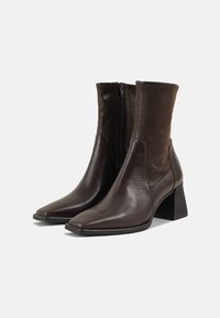 Brown leather ankle boots with a pointed toe, featuring a zip closure and a mid-height block heel, contrasting suede panel at the top.