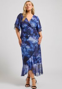 Blå blommig omlotklänning med korta vågiga ärmar, djup V-ringning, ankel-lång fåll och genomskinlig textur; har volangdetaljer i botten.