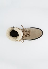 Bottine en suede beige avec un col en fausse fourrure, lacets marron et semelle en caoutchouc noir. Comprend une fermeture éclair pour un accès facile.