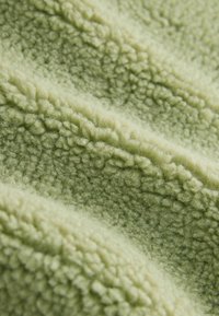Heleroheline tekstuuriga kangas, mille pind on pehme ja karvane. Materjalil on luksuslik laineline muster, mis rõhutab sügavust ja soojust.