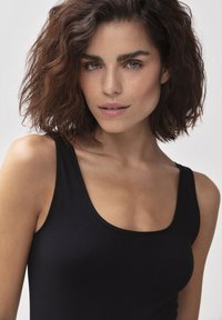 Top senza maniche di colore nero realizzato in materiale morbido; presenta un collo a barca e una vestibilità aderente, con una consistenza liscia e senza motivi visibili.