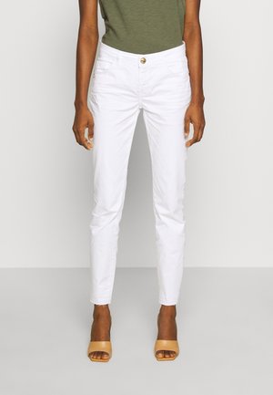 Pantalones de algodón blancos con un corte slim, diseño de cinco bolsillos y detalle de botón dorado, que presentan una textura suave y longitud hasta el tobillo.