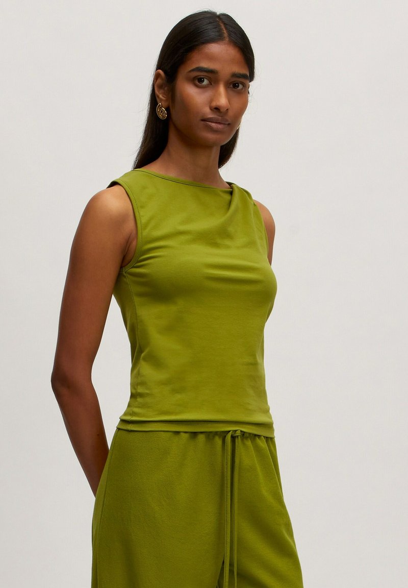 Groene mouwloze top met een ronde halslijn en een aansluitend ontwerp. Gemaakt van gladde stof, met subtiele draping bij de schouders.