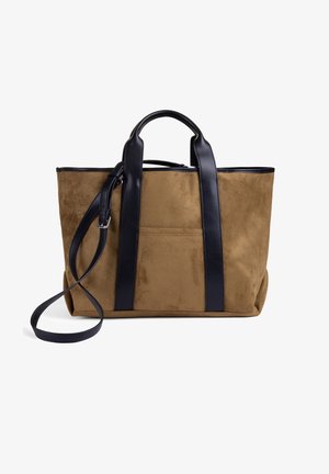Sac cabas en daim marron avec poignées en cuir noir et bandoulière réglable sur fond blanc.