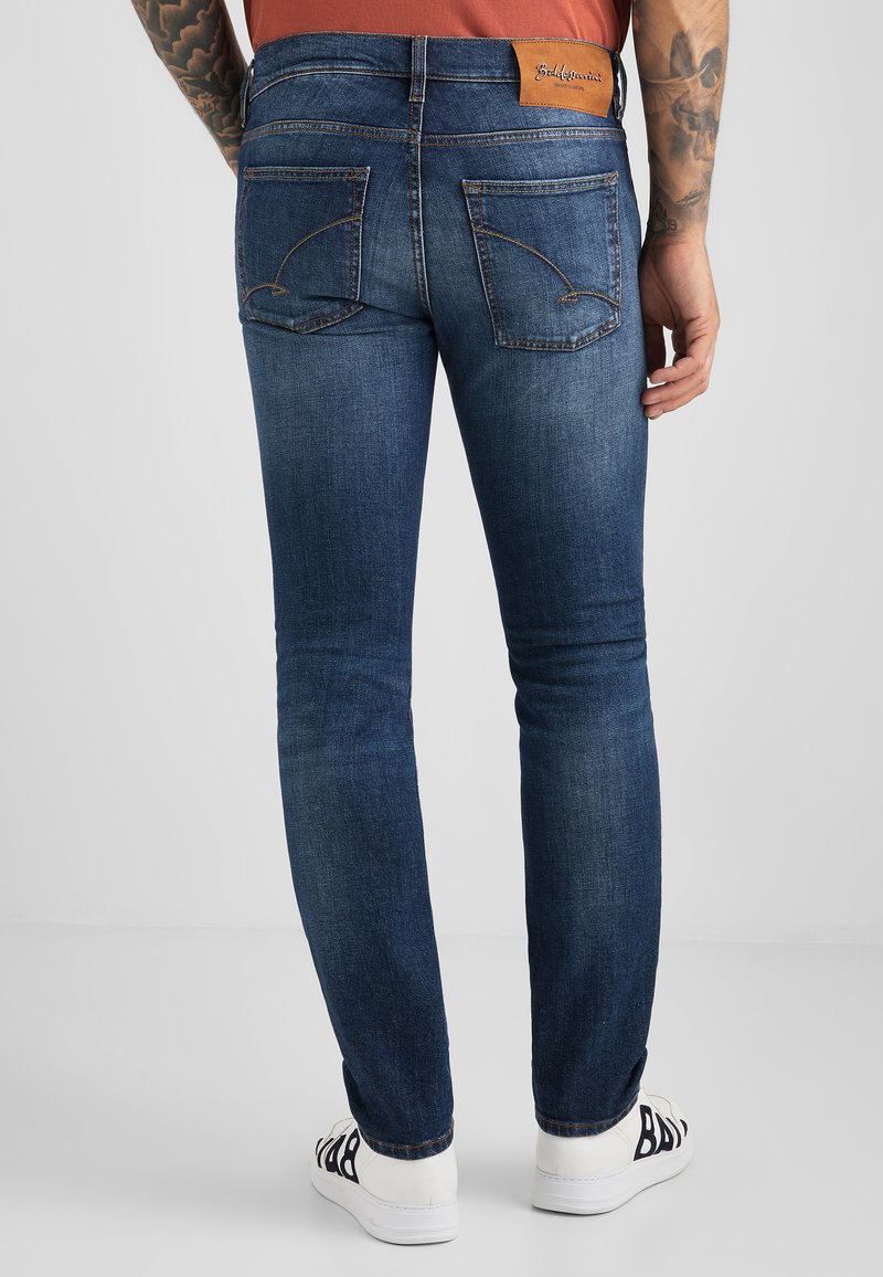 Štíhlé tmavě modré džíny s lehkým šitím, obsahující dvě zadní kapsy a koženou značkovou nášivku na pásu.