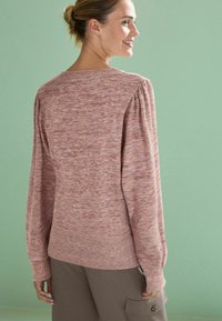 Roosa ja lilla marled kudumiga pullover-sviiter. Omab pikki varrukaid ribiga äärisega ja pehmet tekstuuri. Taust on heles roheline.