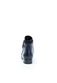 Bottine noire en cuir avec une finition lisse, bout arrondi et un talon court empilé. Elle dispose d'une fermeture éclair sur le côté et d'un tissu texturé au niveau du col.