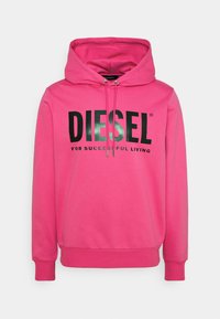 Rosa hoodie i mjukt tyg, med en stor svart logotyp som lyder "DIESEL FÖR FRAMGÅNGSRIKT LIV" över framsidan. Snodd i huvan.