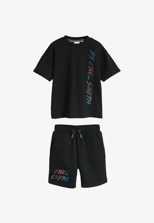 Sort t-shirt med korte ærmer og shorts sæt med farverig "PAUL SMITH" tekst trykt vertikalt på skjorten og på venstre ben af shortsene.