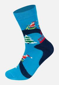 Colorful blue sock with holiday pattern featuring Santa on a bike, snow-covered trees, and a red ski lift against a dark blue background.