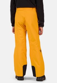 Geel waterdichte broek met een relaxte pasvorm, met zwarte accenten op de zoom en het logo. Soepele textuur met versterkte stikdetails.