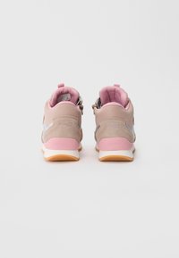 Ein Paar beige und rosa Kinder-Sneaker mit reflektierenden Akzenten, von hinten auf einem weißen Hintergrund betrachtet.