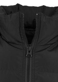 Veste isolante noire avec un col montant et une fermeture éclair centrale. Présente une texture lisse et un motif matelassé horizontal sur le corps.