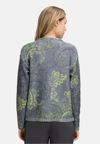 Grauer Pullover mit aufwendigem grünen Paisleymuster. Stricktextur, lange Ärmel und gerippter Saum. Sichtbares Rückendesign und lockere Passform.