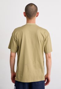 Khaki bavlněné tričko s krátkým rukávem, kulatým výstřihem a volným střihem. Hladká textura, jednoduchý design, pohled zezadu.
