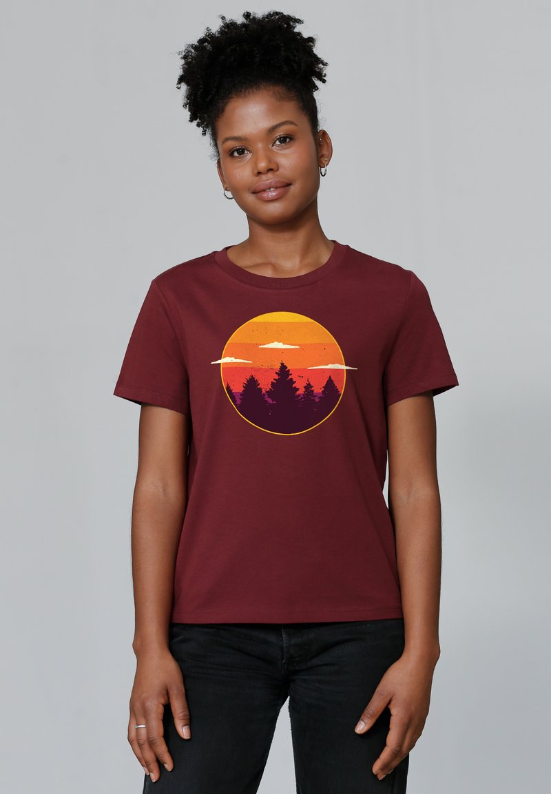 T-shirt en coton bordeaux avec un graphique de coucher de soleil circulaire aux teintes orange, jaune et violet, et des silhouettes d'arbres en bas.