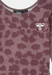 Bordeaux top met een luipaardprint, met een gladde textuur en een ronde halslijn. Een klein wit logo is op de borst geplaatst.