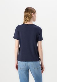 Marineblå bomulds T-shirt med korte ærmer, rund halsudskæring og afslappet pasform, parret med lyseblå denimjeans.