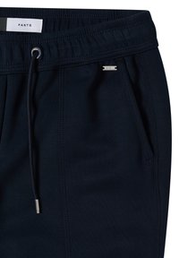 Pantalon à ceinture élastique bleu marine foncé avec cordon de serrage, poche latérale et petite étiquette métallique de la marque près de l'ouverture de la poche.