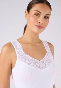 Witte tanktop met een geschulpte kantencol waardoor het een elegante uitstraling heeft, gemaakt van een textuurstof. Ontworpen met brede schouderbanden voor extra comfort.