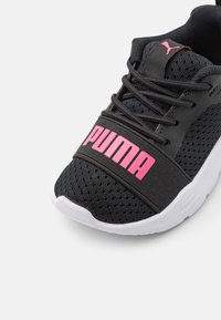 Zwarte sportieve schoen met een mesh bovenkant, een roze "PUMA" logo, zwarte veters en een witte zool met textuurdetail.